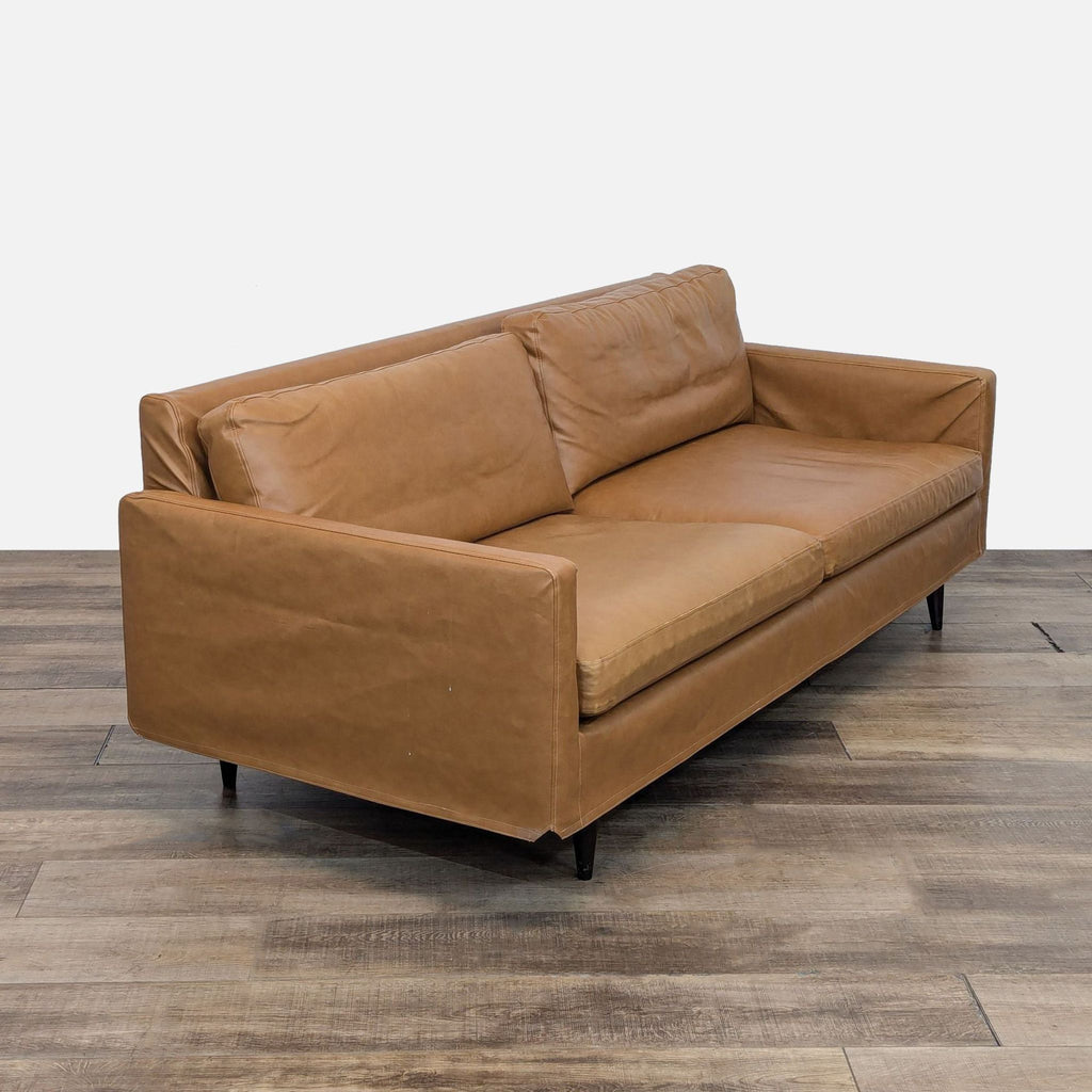 a brown leather sofa with a black metal legs.