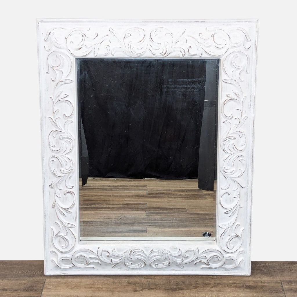 a large white mirror with carved white wood frame.