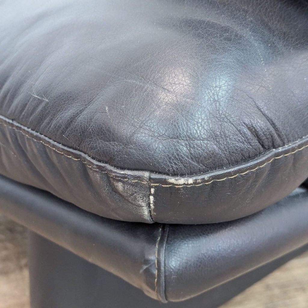 a black leather chair with a black leather seat and a metal base.