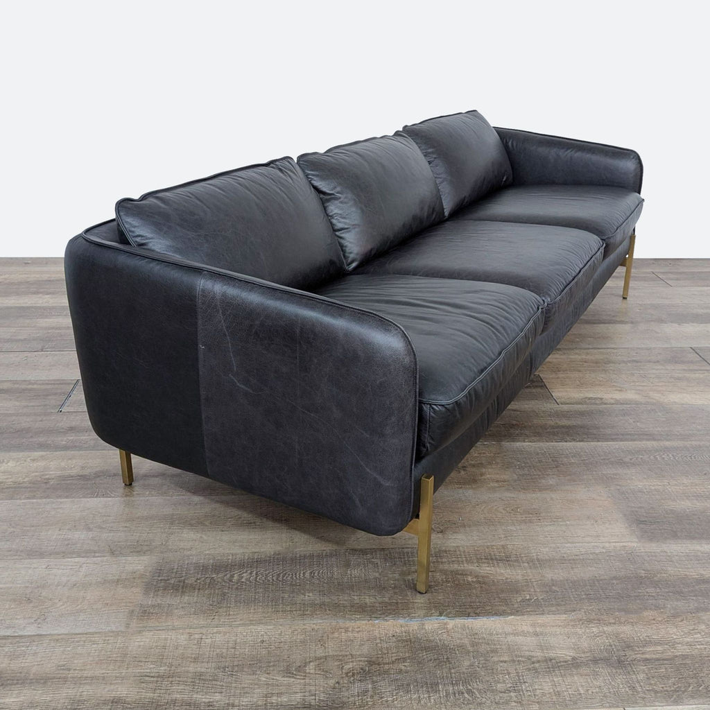 a black leather sofa with gold legs.