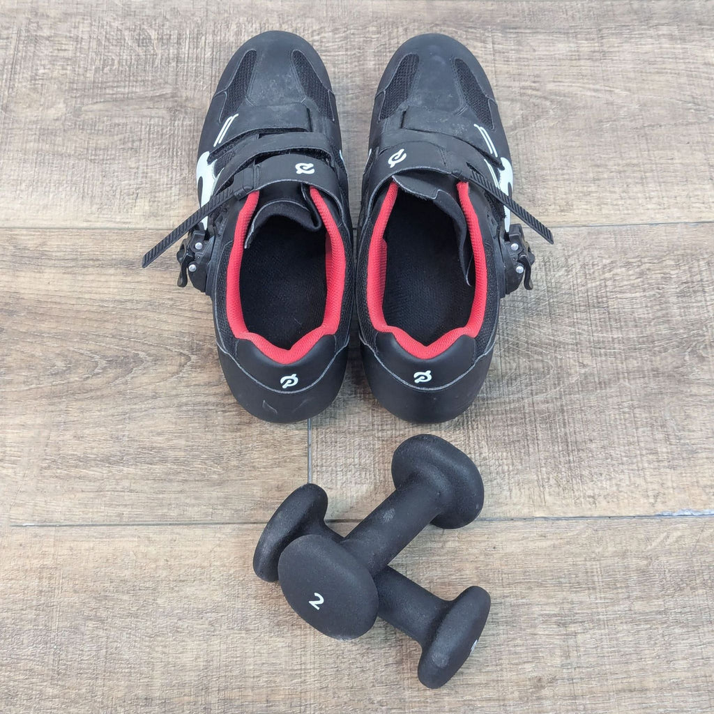 a pair of black and red shoes and a dumbbell on a wooden floor.