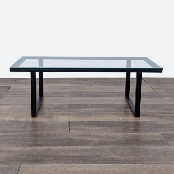 a glass top coffee table with a black frame.