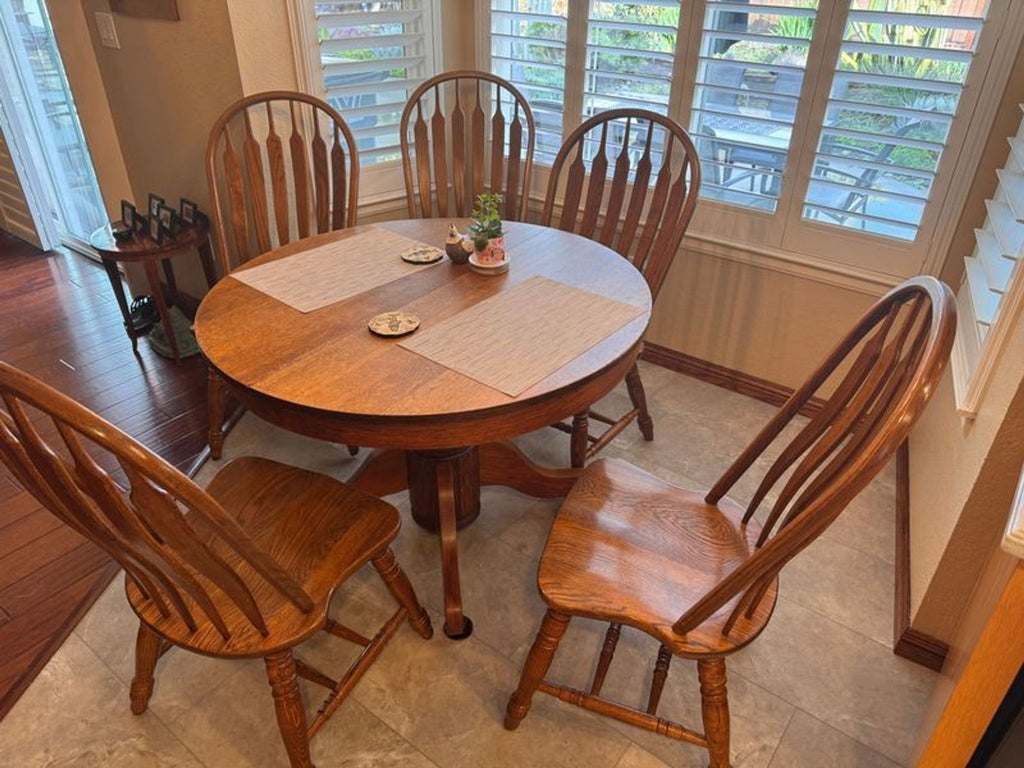 1. Reperch dining set with round wooden table and six matching spindle-back chairs in a bright kitchen corner.
