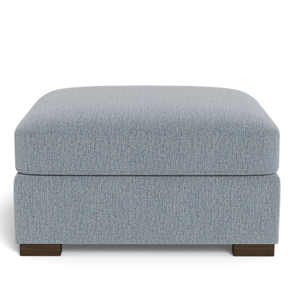 a grey linen ottoman with a dark brown footstool.