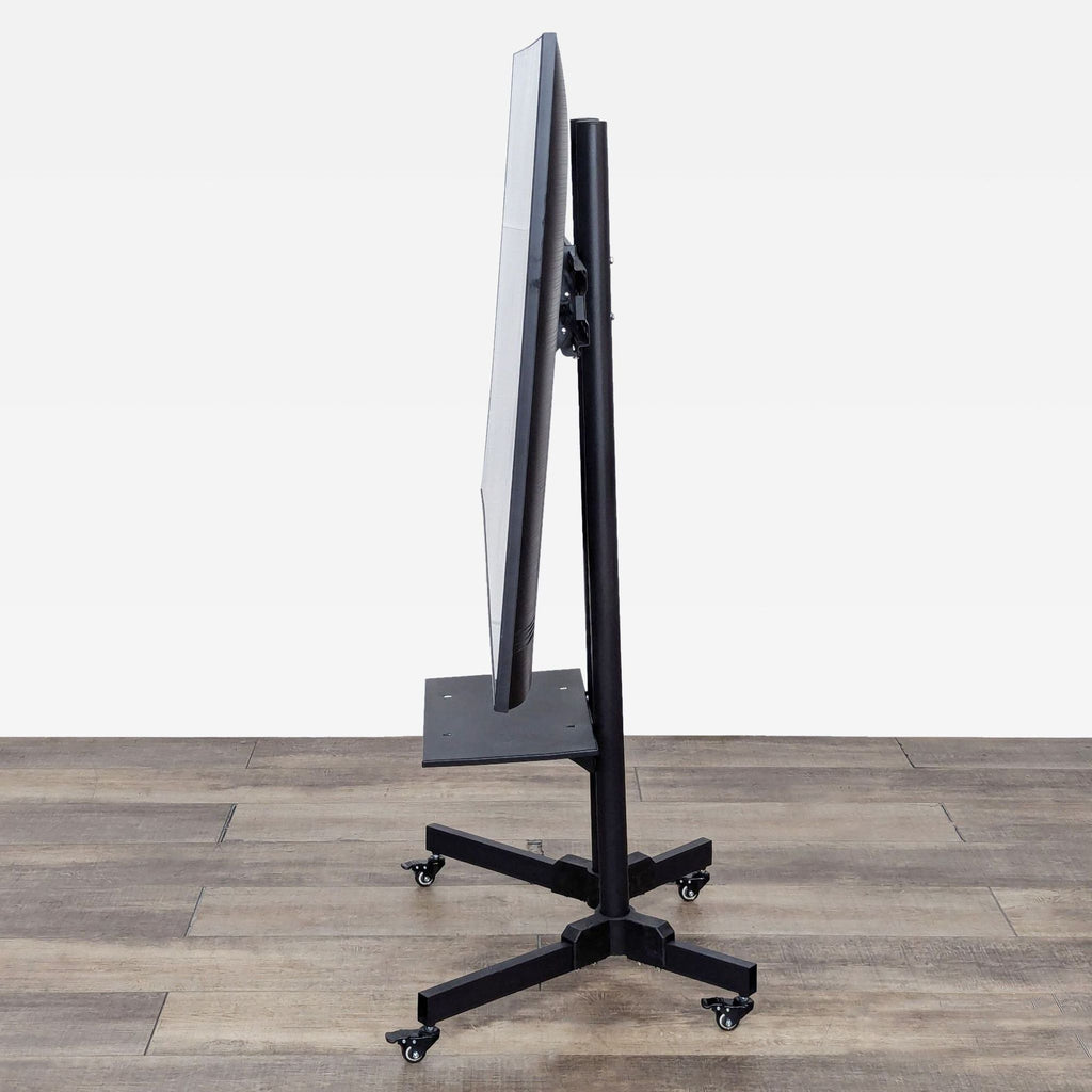 a large black standing monitor stand on a wooden floor.