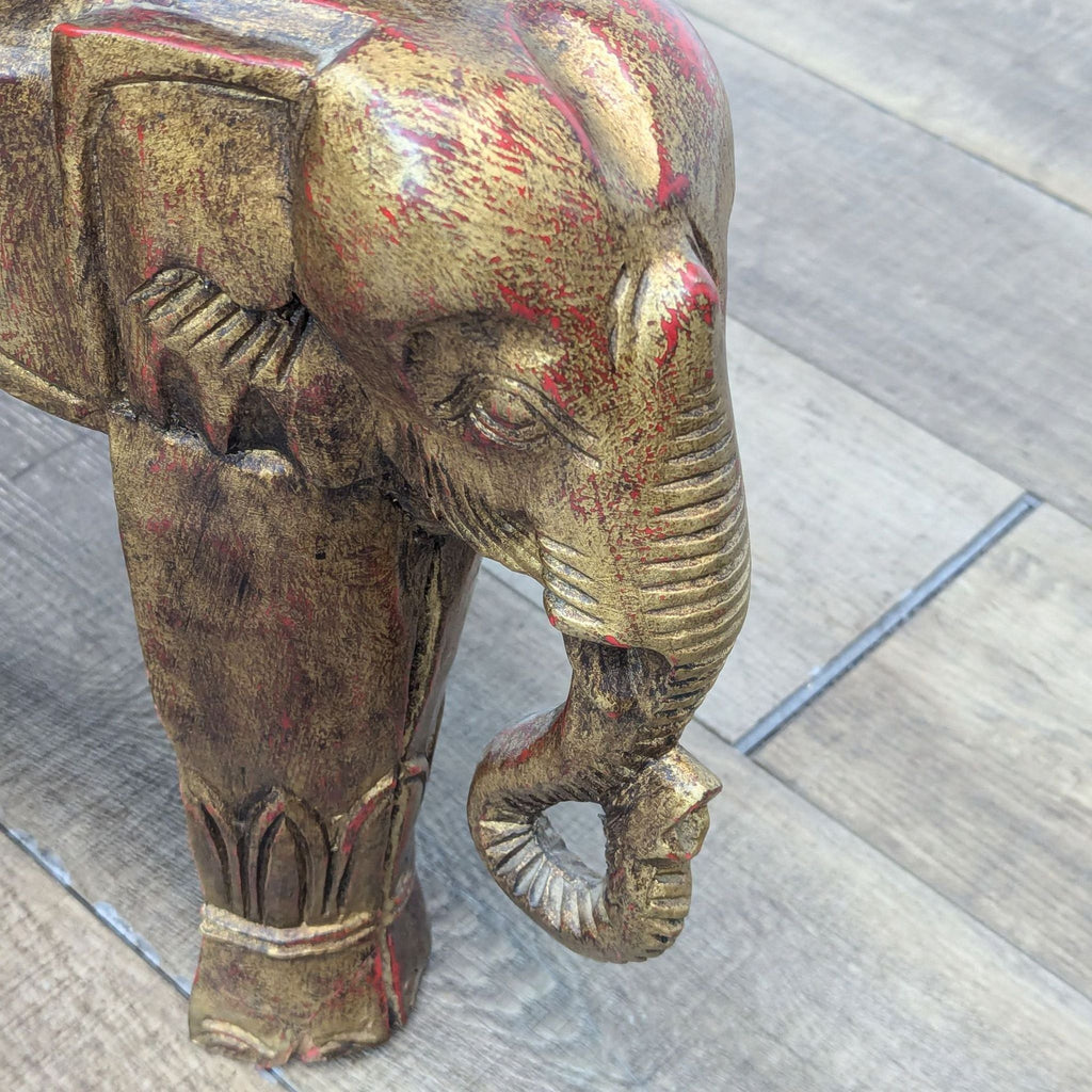 a large brass elephant statue on a wooden floor.