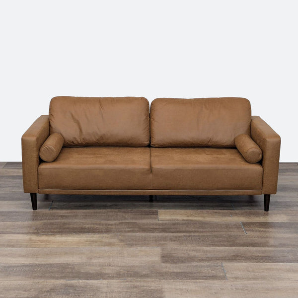 a brown leather sofa in a room with a white wall.