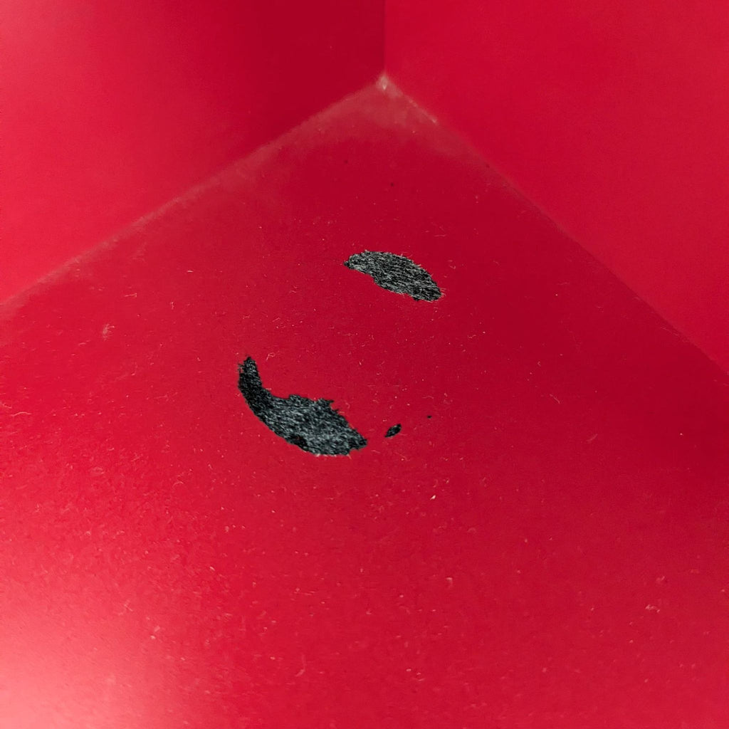 a red and white bird sitting on top of a red object 