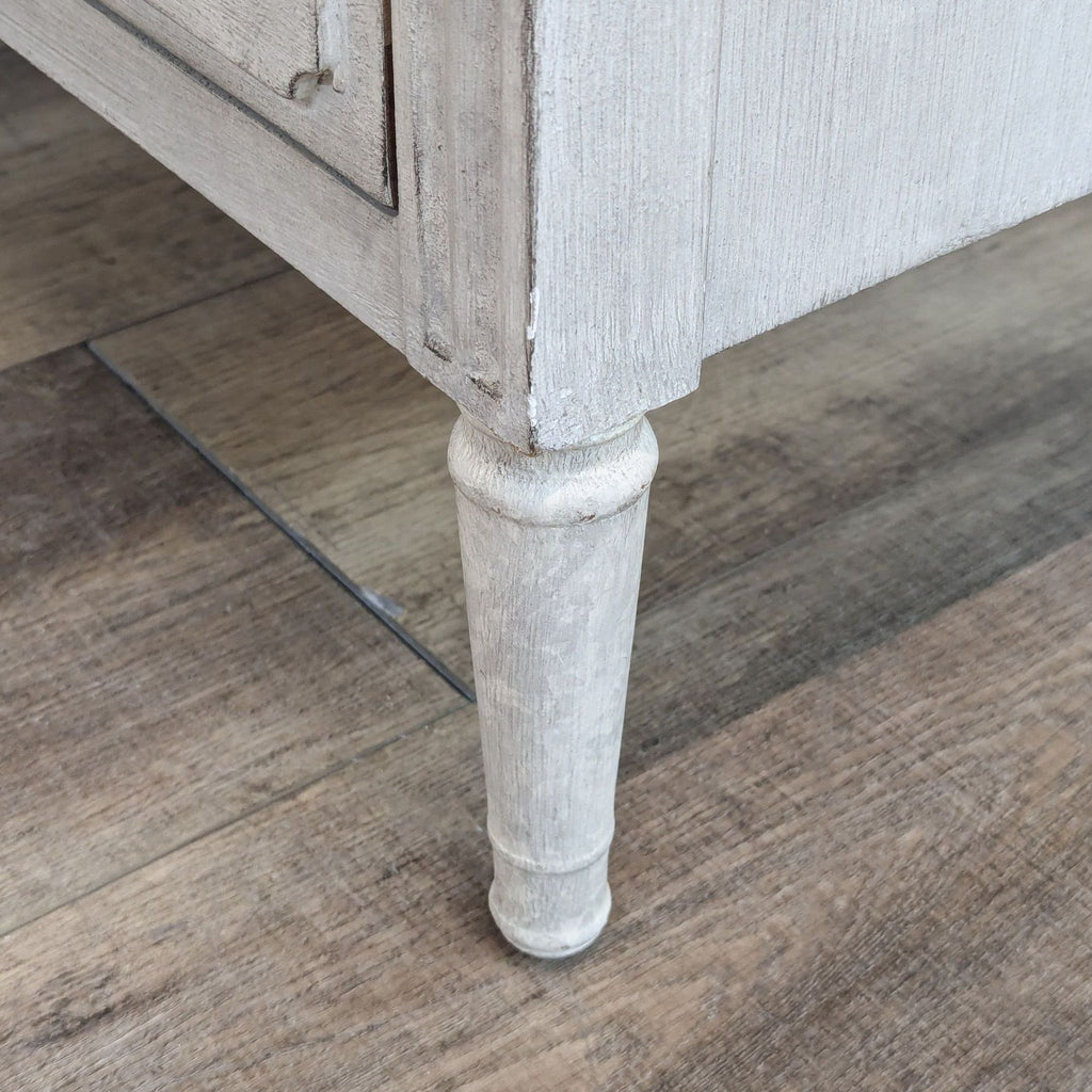 a white vase sitting on the ground next to a wall 