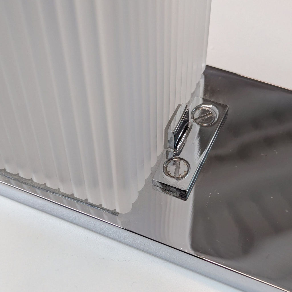 Contemporary wall sconce showcasing a shiny chrome frame paired with a textured frosted glass cover.  