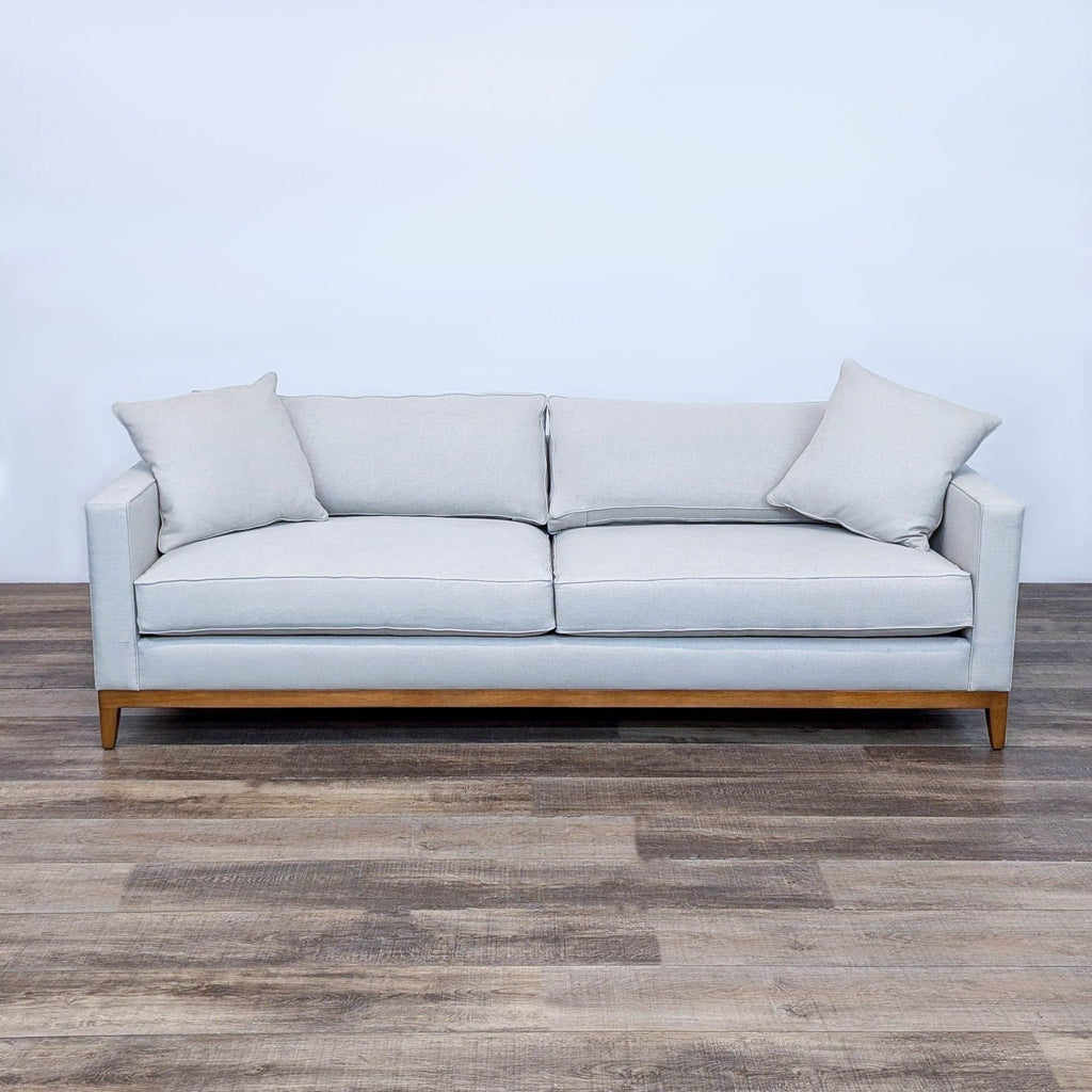 Modern 3-seat sofa with fabric upholstery, wood base, tapered legs, and matching throw pillows.