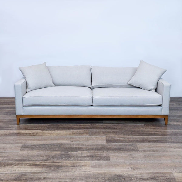 Modern 3-seat sofa with fabric upholstery, wood base, tapered legs, and matching throw pillows.