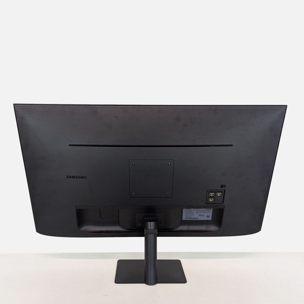 a black computer monitor sitting on top of a wooden table 
