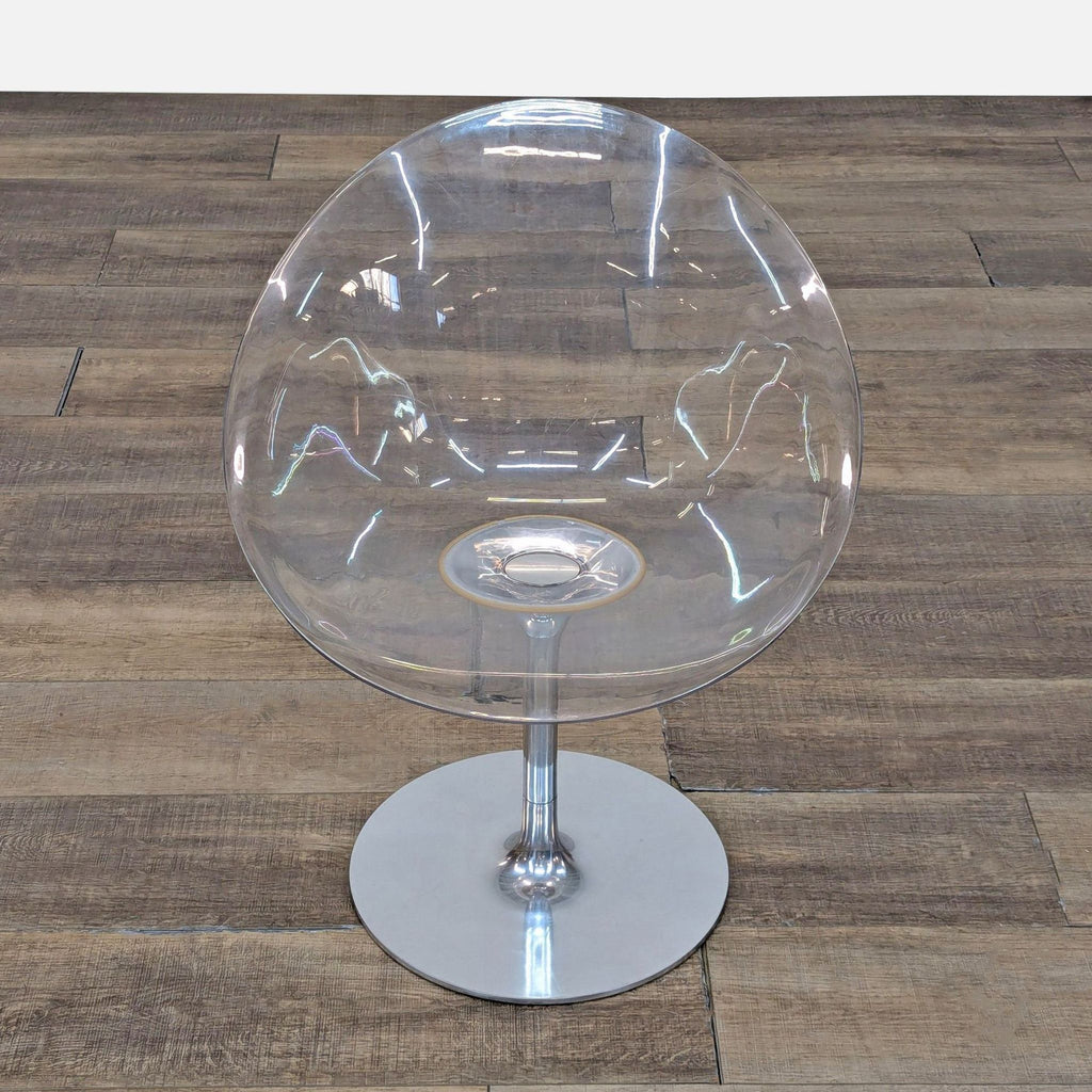 3. Overhead view of Kartell lounge chair with crystal clear egg-shaped shell and round aluminum base on wood floor.