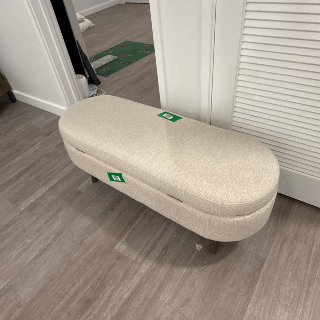 2. Oval cream ottoman by Walmart Sofa with wooden legs, shown indoors on wood floors with green stickers attached.
