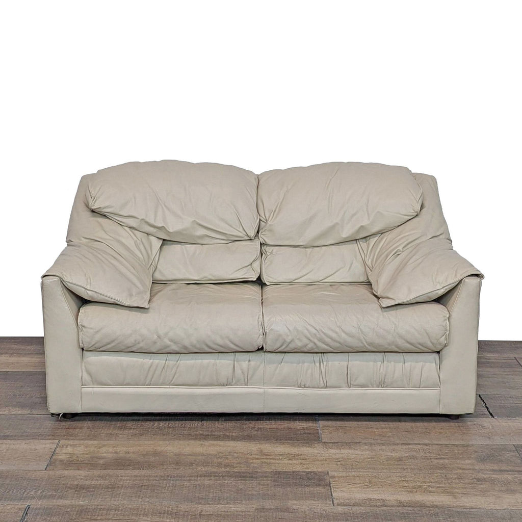 Front view of a beige leather loveseat with plush cushions.