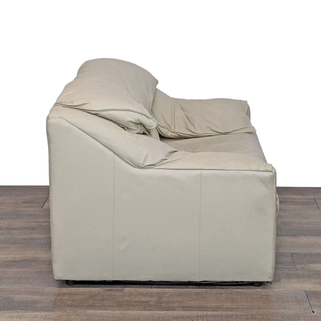 Side view of a beige leather loveseat showing its soft, plush cushions.