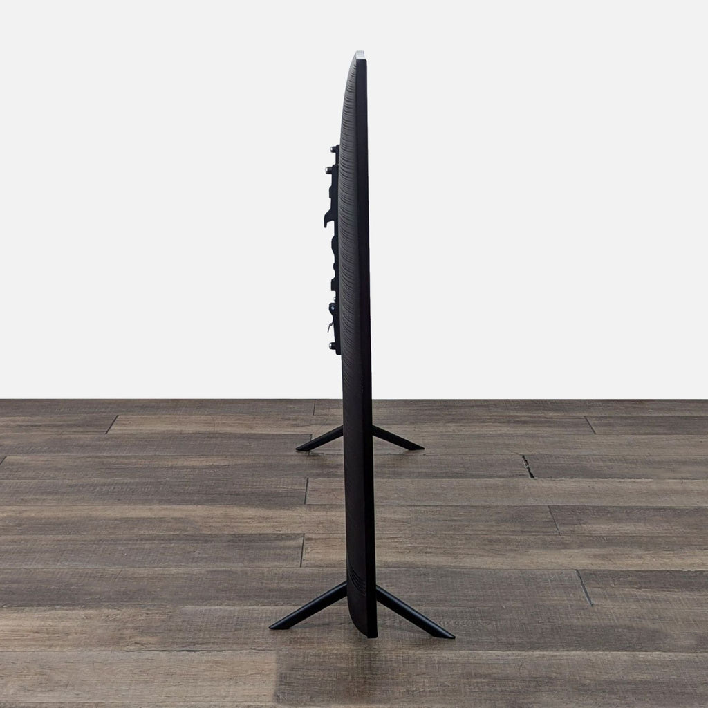 Slim profile of a brand new Samsung TV on wooden floor.