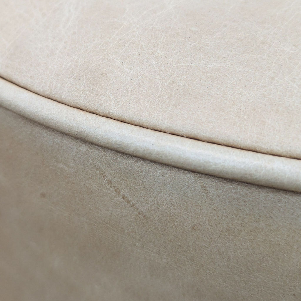 Close-up of tan ottoman’s textured leather material.