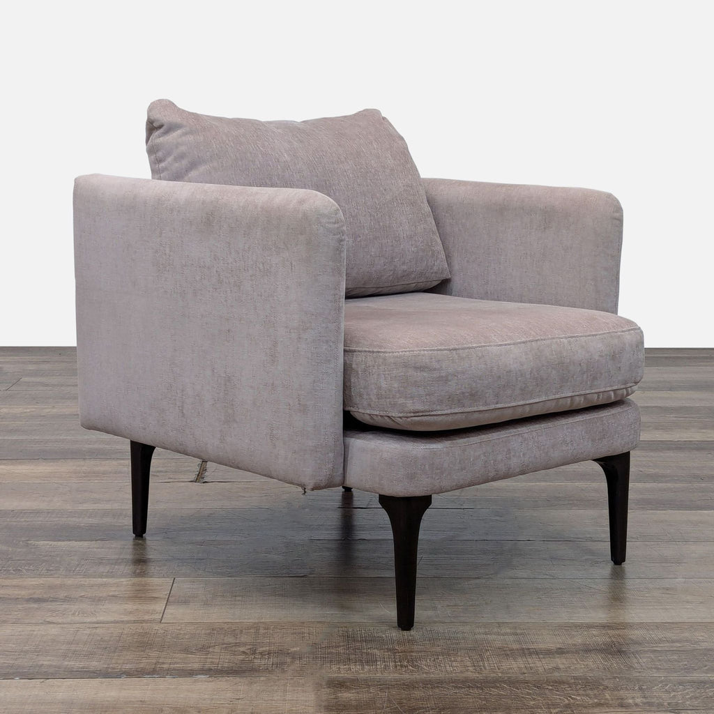 Angled view of a beige upholstered chair by West Elm with solid wood legs.