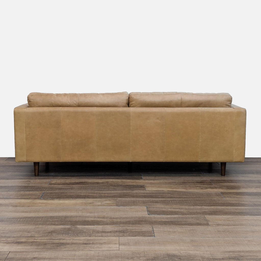 Back view of the West Elm sofa highlighting the smooth leather upholstery and wood legs.