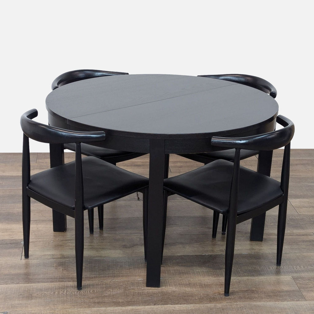 Extendable black wood round dining table with matching chairs.