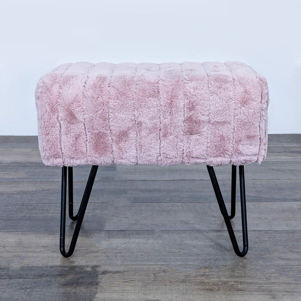 Pink faux fur stool with metal hairpin legs on wooden floor.