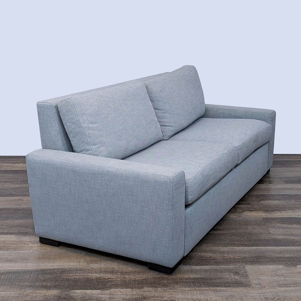 Side view of a stylish gray sofa with deep cushions and clean lines.