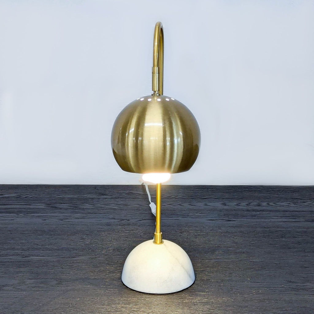 Marble-based table lamp with brass arm and shade.