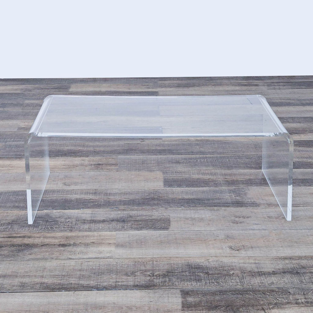 Clear acrylic coffee table on a wooden floor, showcasing modern minimalist design.