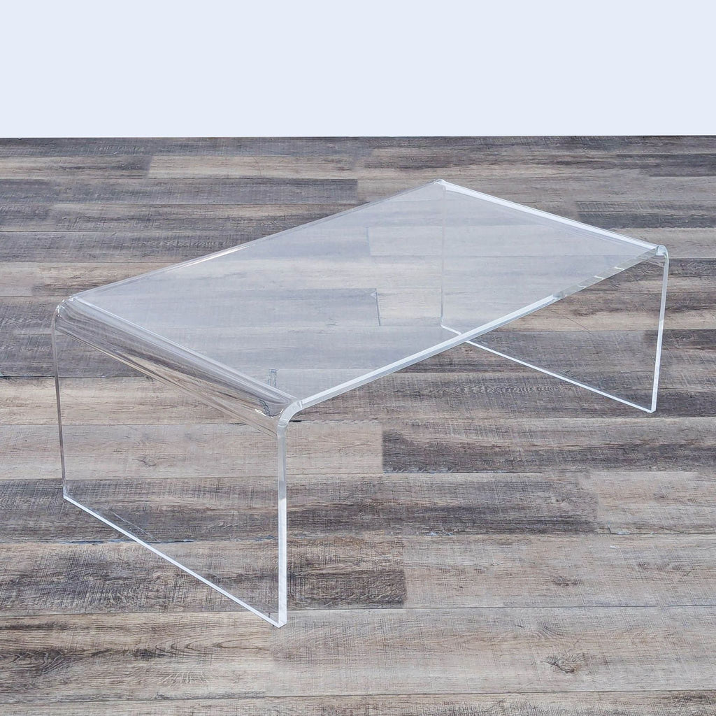 Sleek transparent coffee table with curved edges, placed on a rustic wood floor.