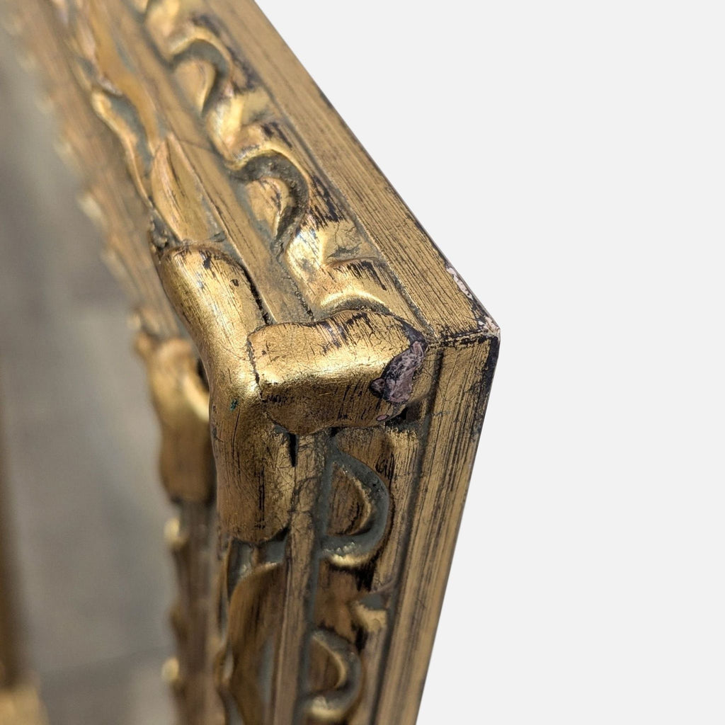 3. Detailed corner view of a gold mirror frame, highlighting intricate patterns and slight wear.