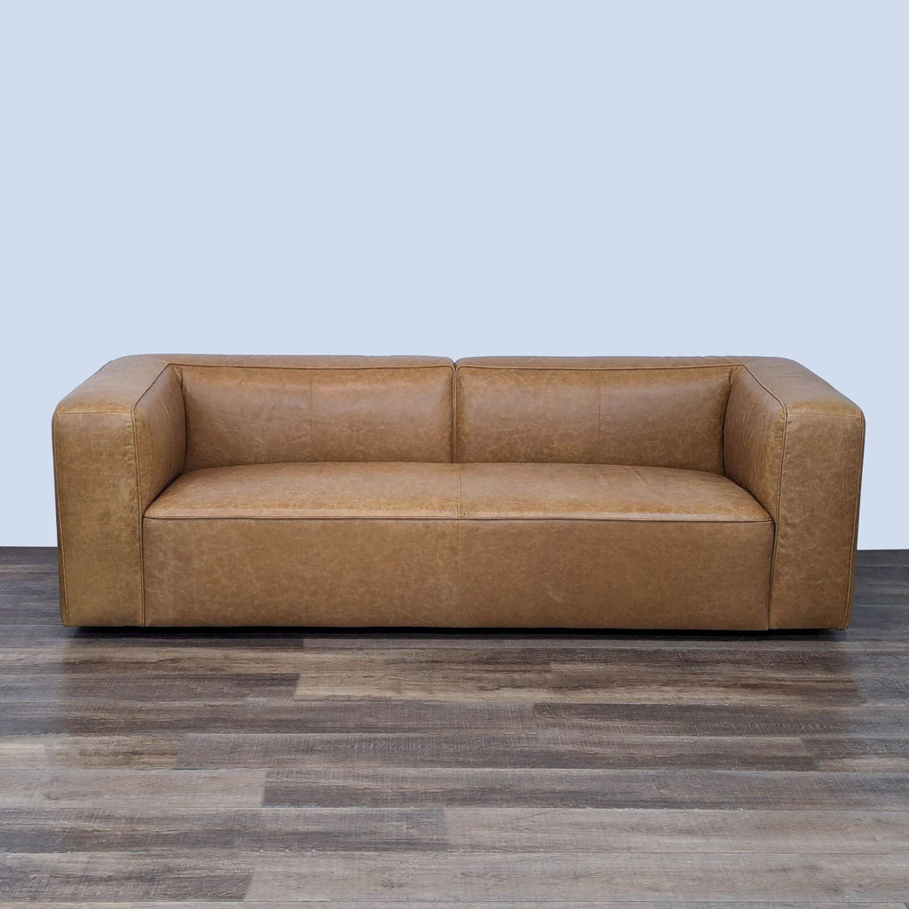 a brown leather couch sitting on a hard wood floor 