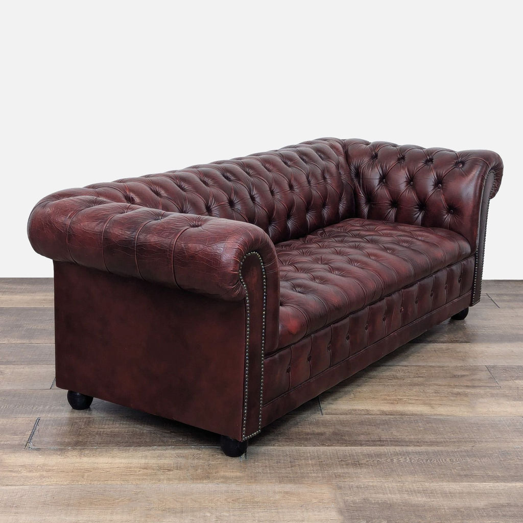 Angled view of 3-seat Chesterfield sofa in red leather, featuring tufted upholstery and trim.