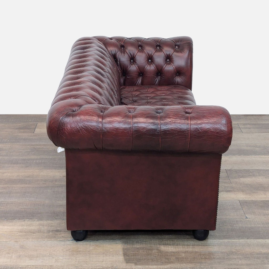 Side view of a red leather Chesterfield sofa, showing tufted design and nailhead details.