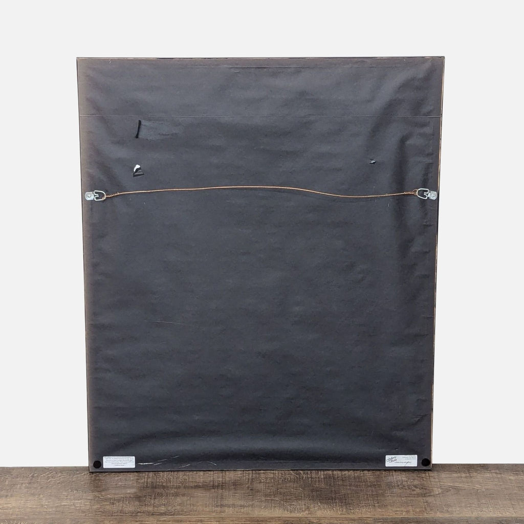 a black piece of wood sitting on top of a wooden floor 