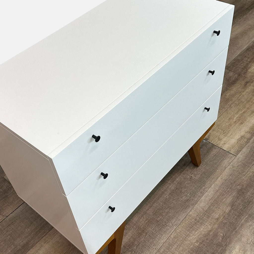 a white wooden box sitting on top of a wooden floor 