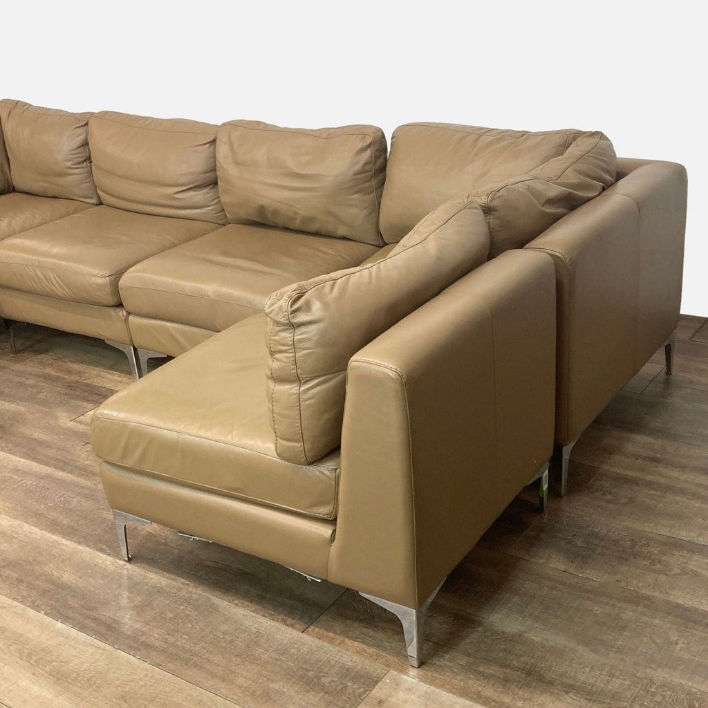 Right-arm chaise of a light brown leather sectional sofa with modern angled legs.