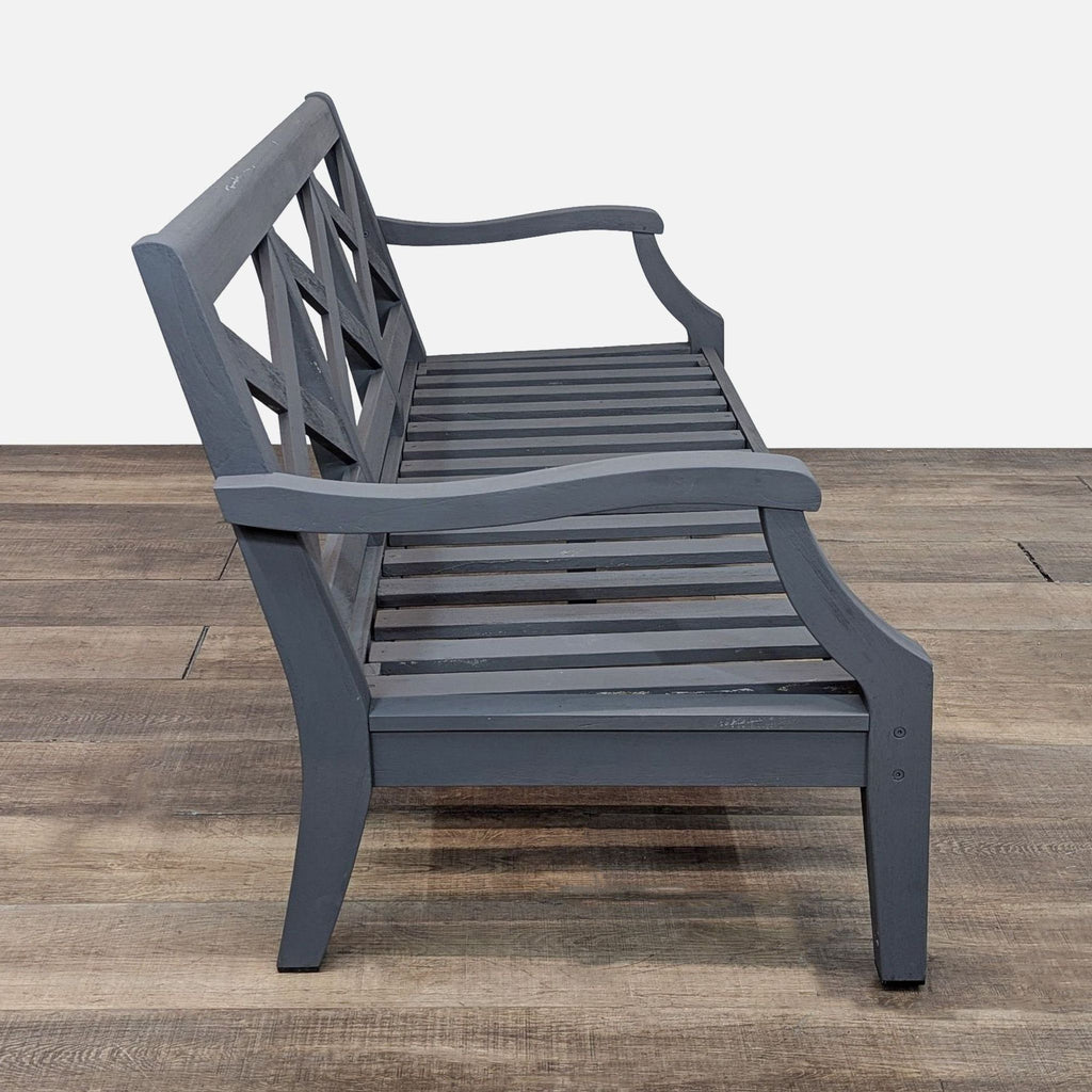 Side view of a gray bench showing the curved armrests and slatted seat.  