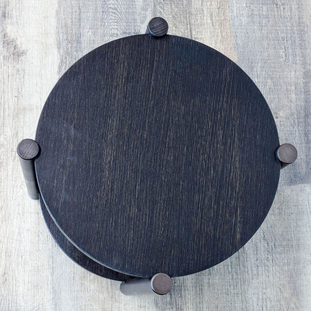 Top view of a dark, two-tiered round table with beech veneer surface.