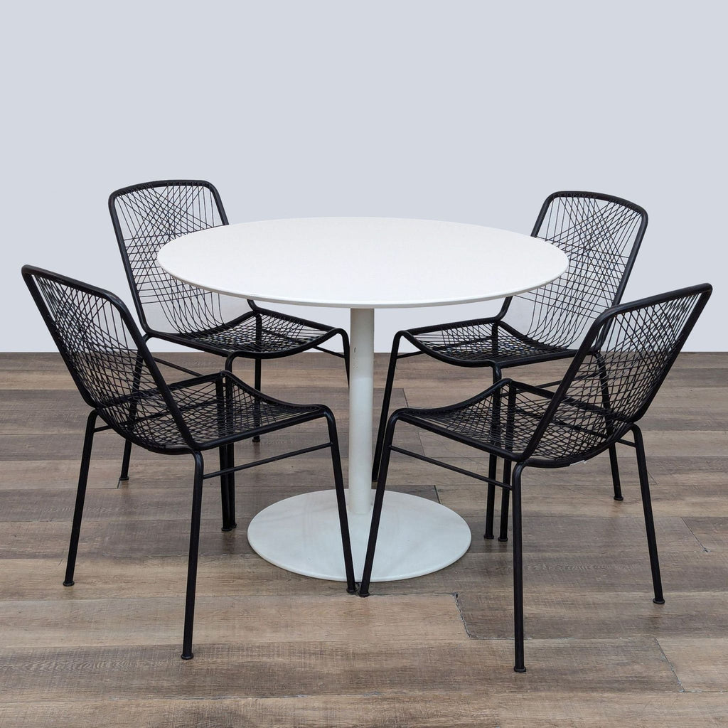 Dining set with white round table and black metal chairs.  