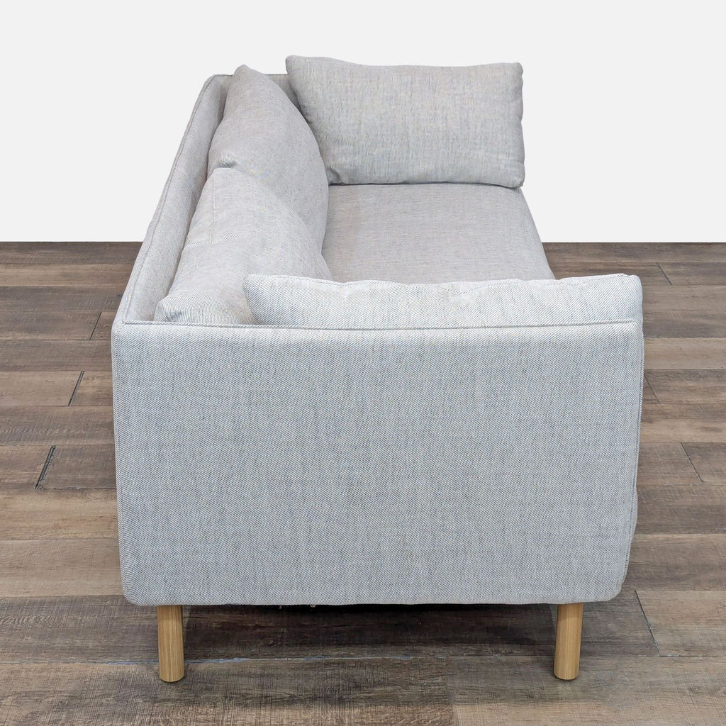 Side view of Wells sofa, showcasing slim frame and plump cushions on wooden legs.