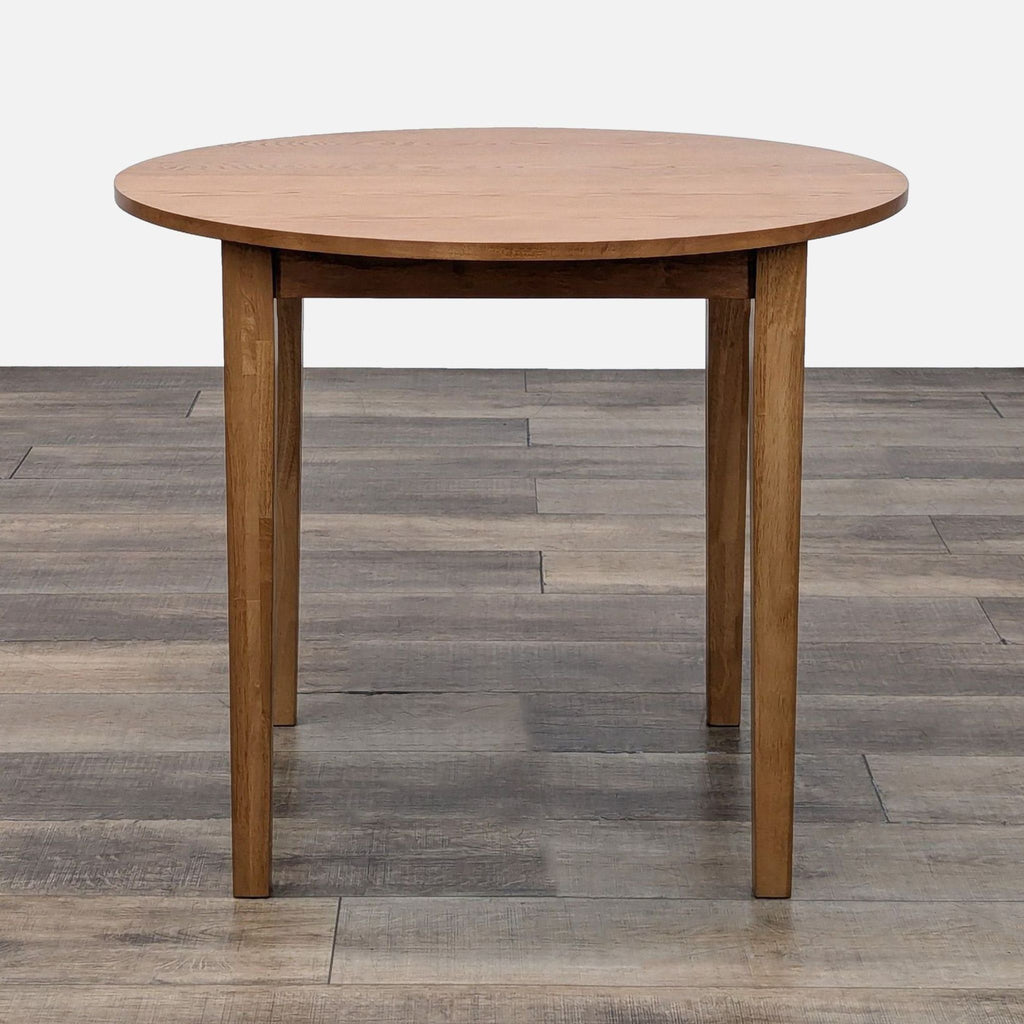 Litfad dining table with round top and simple wooden legs.