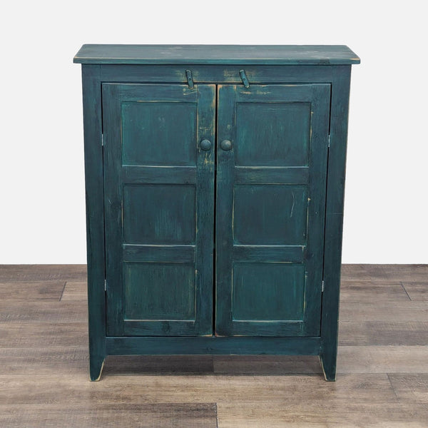 Reperch cabinet with distressed teal finish and paneled doors.