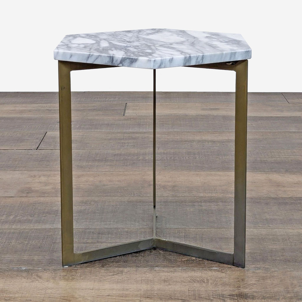 Hexagon marble top table with brushed metal legs on wooden floor.