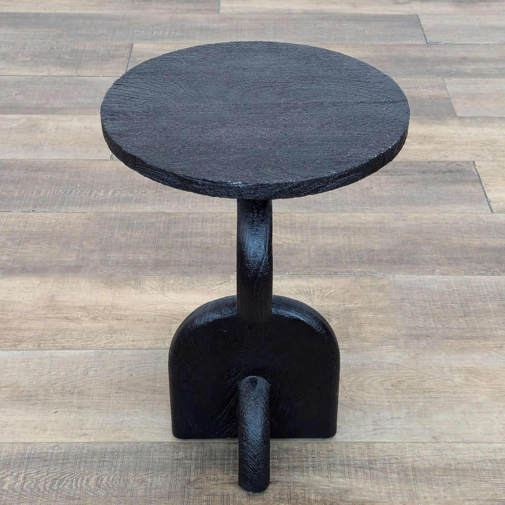 Sculpted pillar silhouette table made from dark tropical hardwood, shown on wooden flooring.