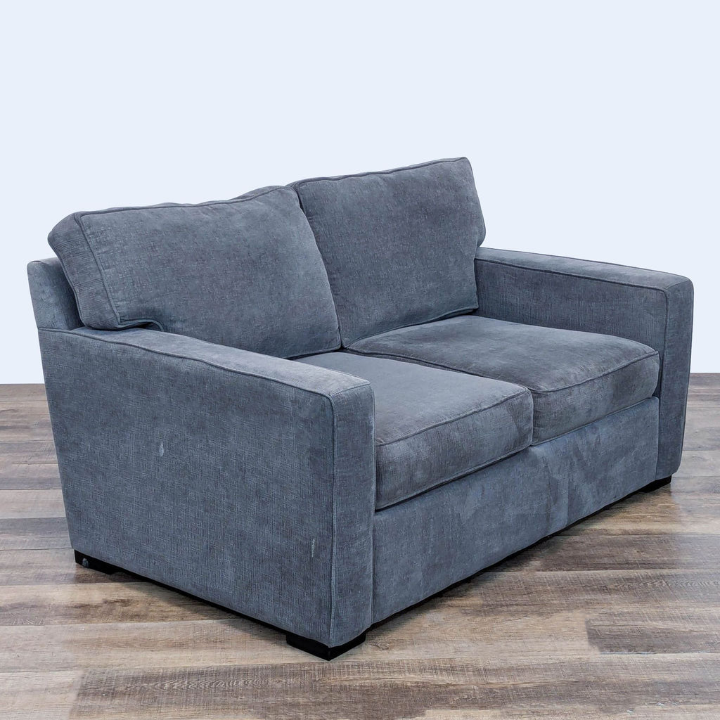 Angled view of a gray loveseat, showcasing its clean lines and textured fabric.