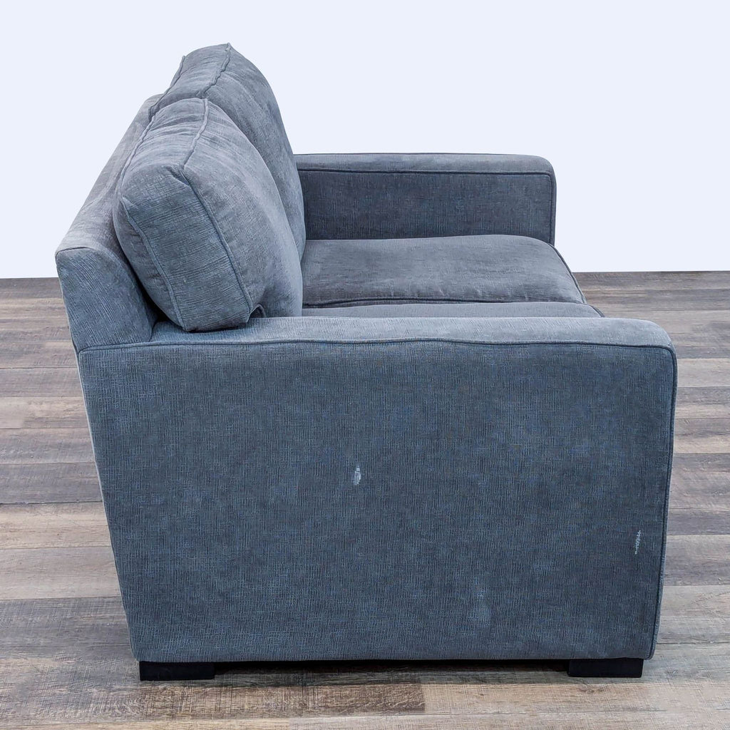 Side view of a gray loveseat with structured cushions and tailored upholstery.