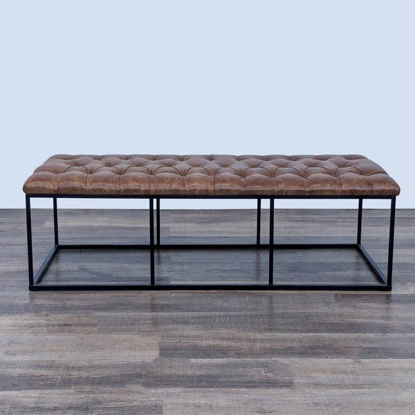 Modern bench with tufted brown leather seat and black metal frame on wooden floor.