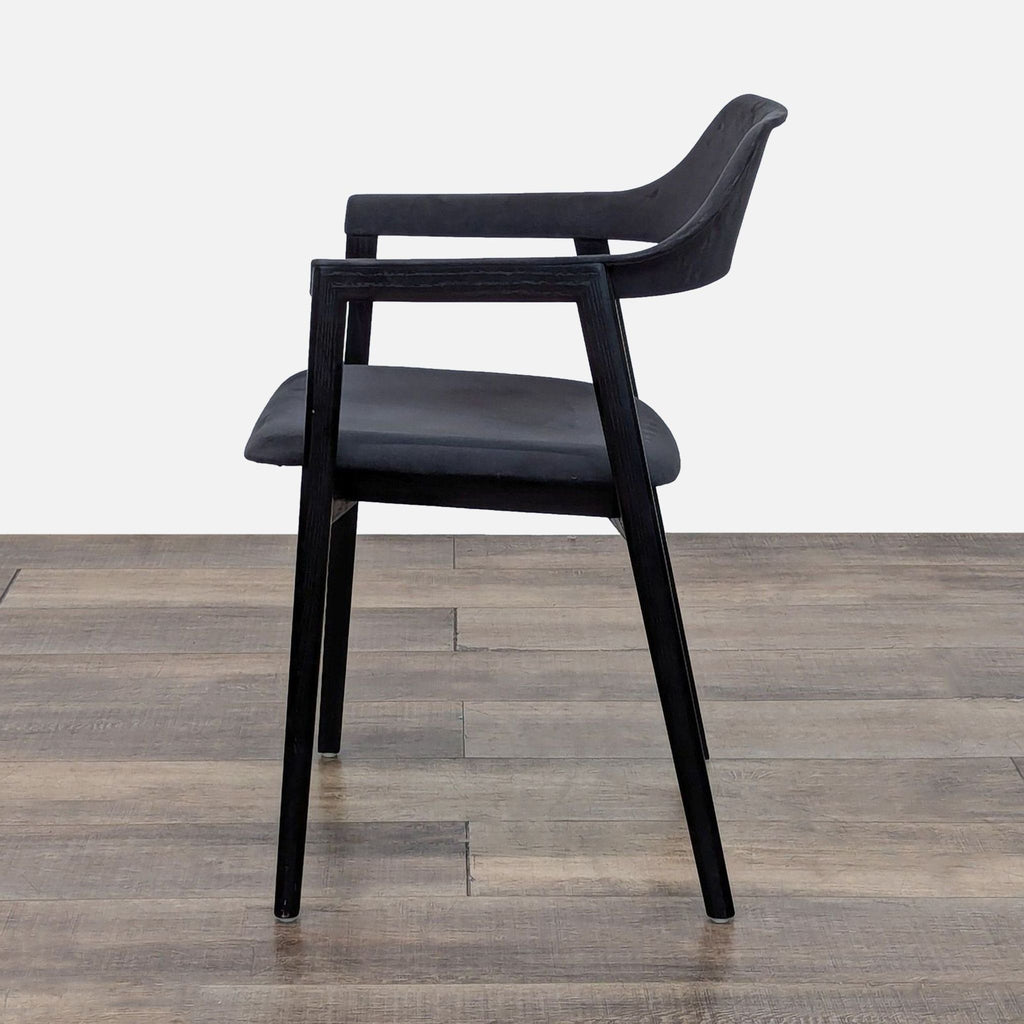Side view of a matte walnut frame chair with continuous black leather.